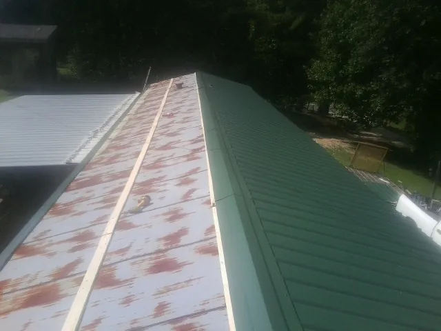 Old rusted panels beside newly installed green metal roofing — Wind Damage Roof Repair by Roofing Brothers in Fort White