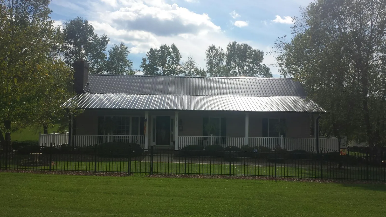 Gray metal roof on a brick ranch with a full width front porch — Gutter Guard Installation work by our crew in Fort White