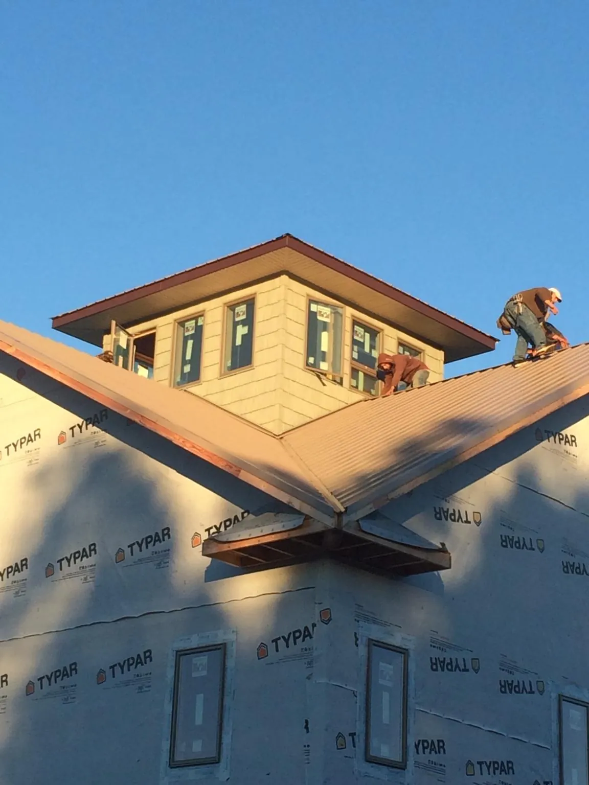 Roofers working around a rooftop cupola on a new metal roof at sunset — Roof Waterproofing in Fort White by Roofing Brothers